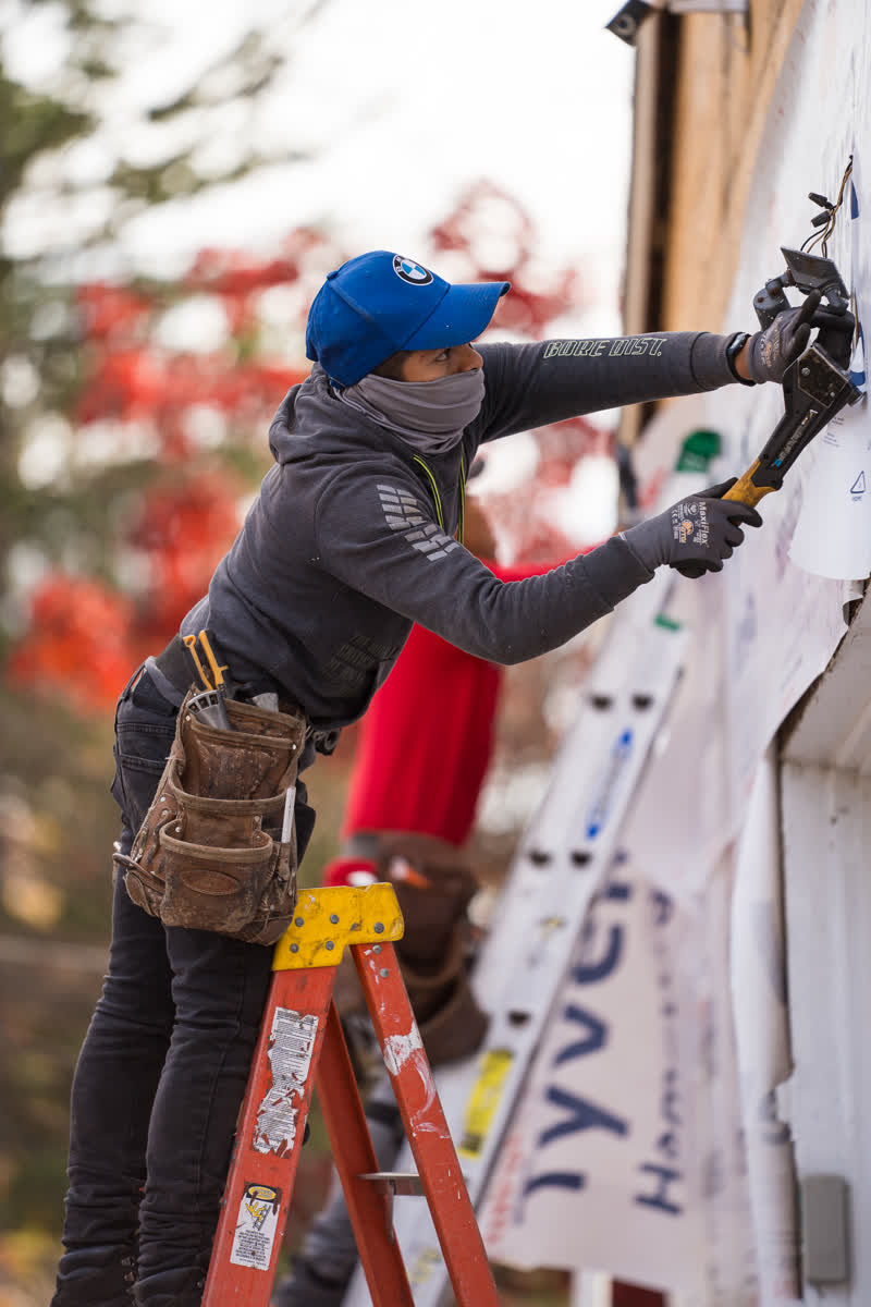 Crew member installing house wrap and siding
